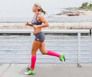 woman running in pink compression leg sleeves